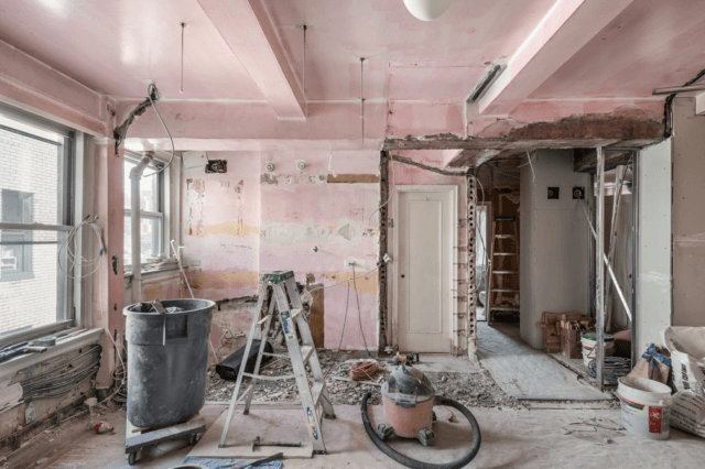 Interior residential property under renovation with exposed walls, construction debris, ladder, and remodeling equipment.